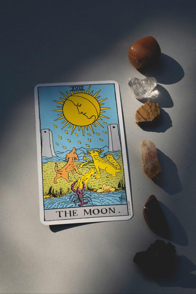 The moon tarot card in moonlight shadow and energy crystals beside - Full Moon Tarot Reading